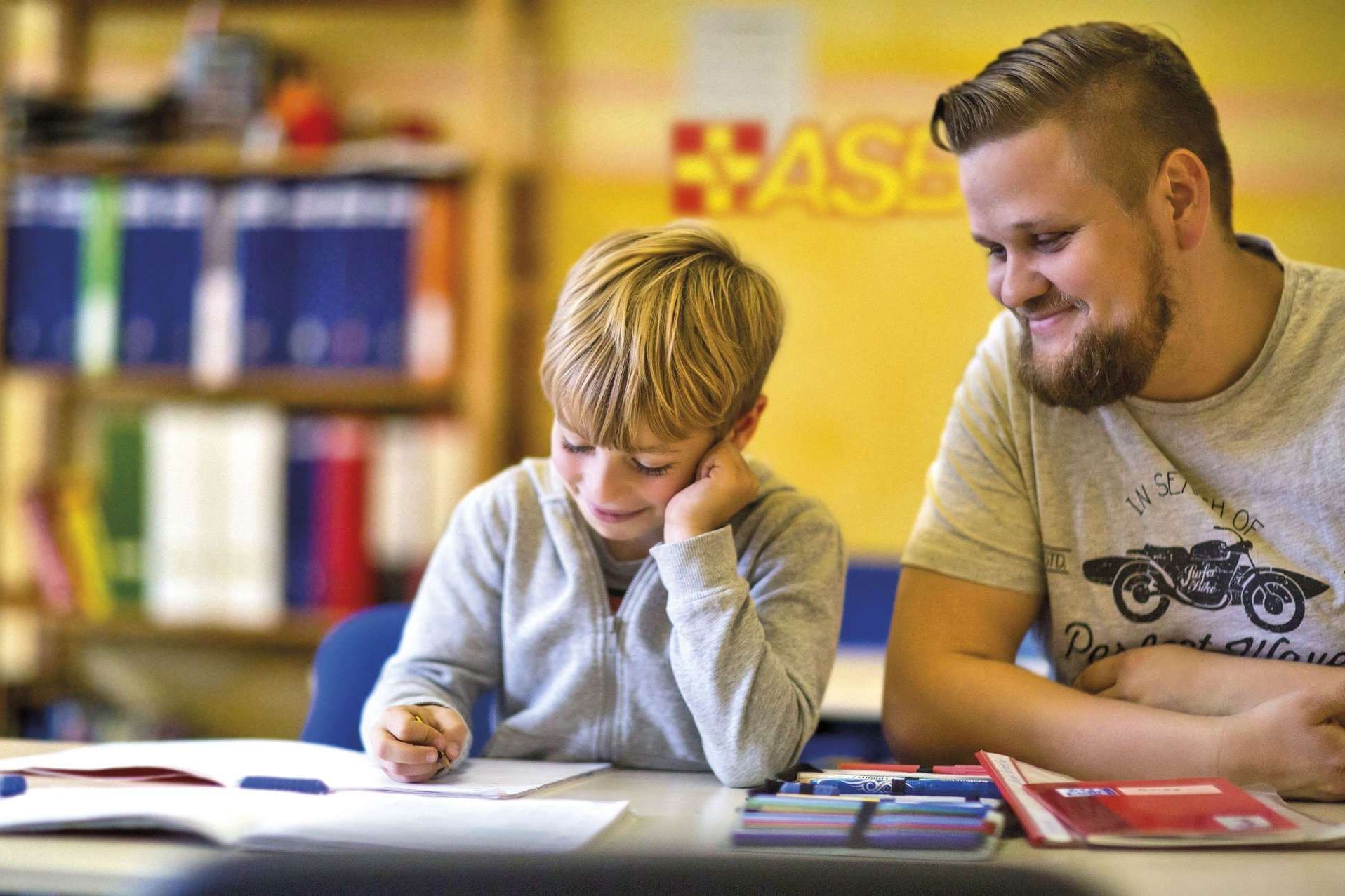 Ein junger Mann vom ASB hilft einem Schüler bei den Hausaufgaben