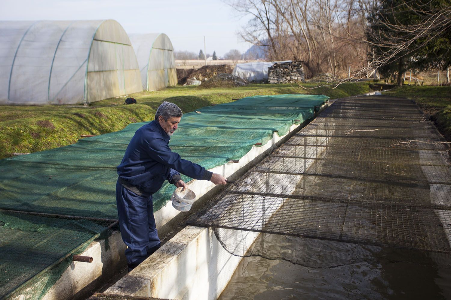 Gründung von sozialen Unternehmen auf dem Balkan Ein Mann füttert Fische in einem Aufzuchtbecken