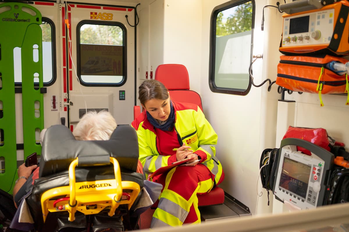 Notfallsanitäter-Ausbildung-Rettungswagen-ASB-K-Müller.jpg Angehende Notfallsanitätering im Rettungswagen beim Gespräch mit einem Patienten. Fitness und Verantwortungsbewusstsein sind wichtige Voraussetzungen für diesen Beruf.
